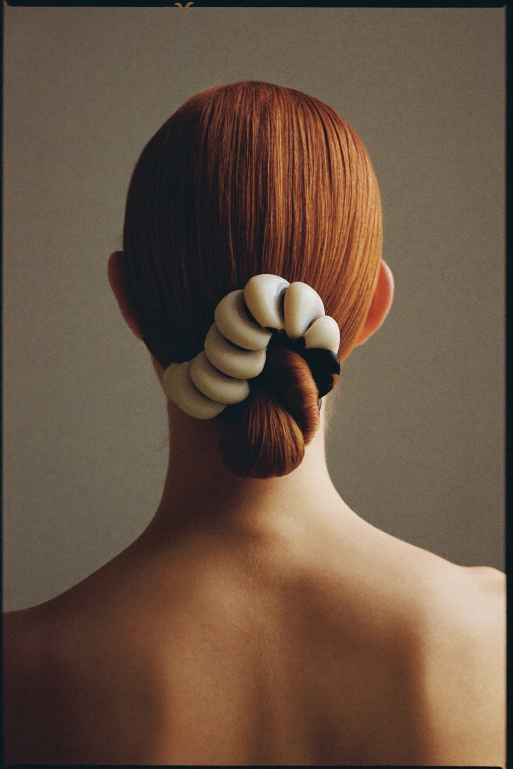 A sleek chignon held by a sculptural barrette, seen from behind