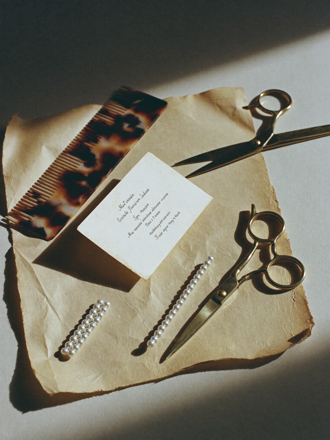 A comb, shears and pearl pins laid on aged paper